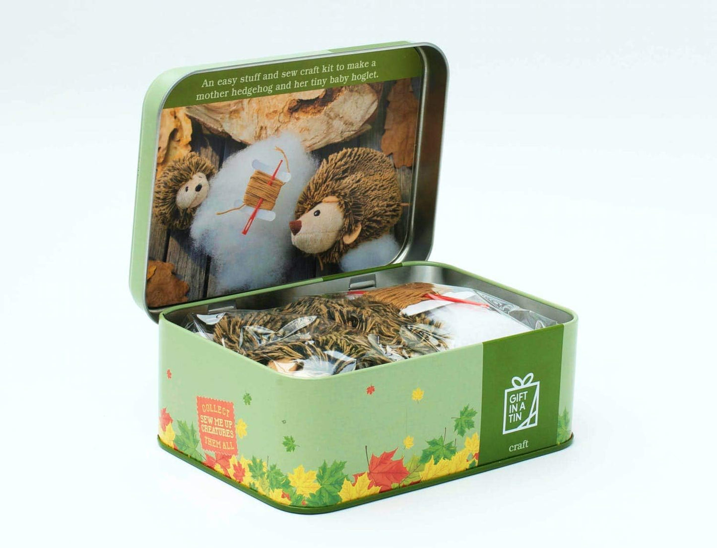 Open tin box with craft materials and hedgehog-themed packaging on a white background