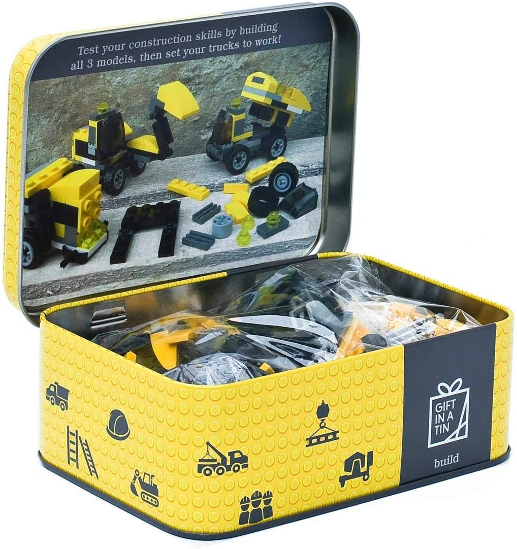Toy construction set in a tin with yellow and black design, featuring toy trucks and building blocks.