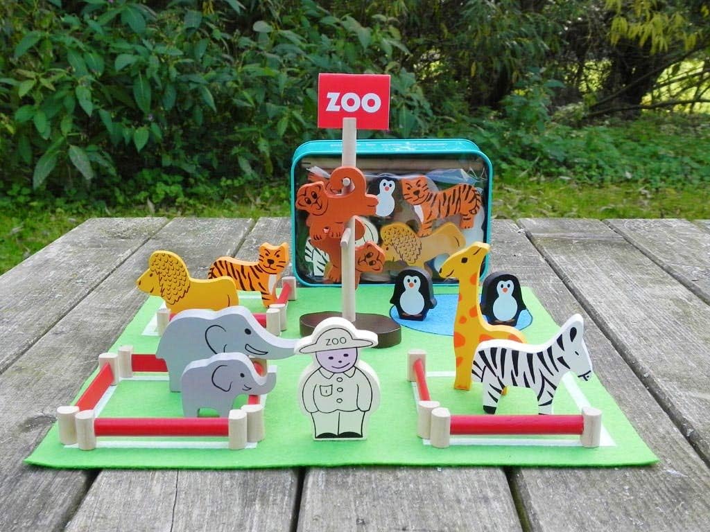 Wooden animal toys on a green mat with a 'Zoo' sign, outdoors.