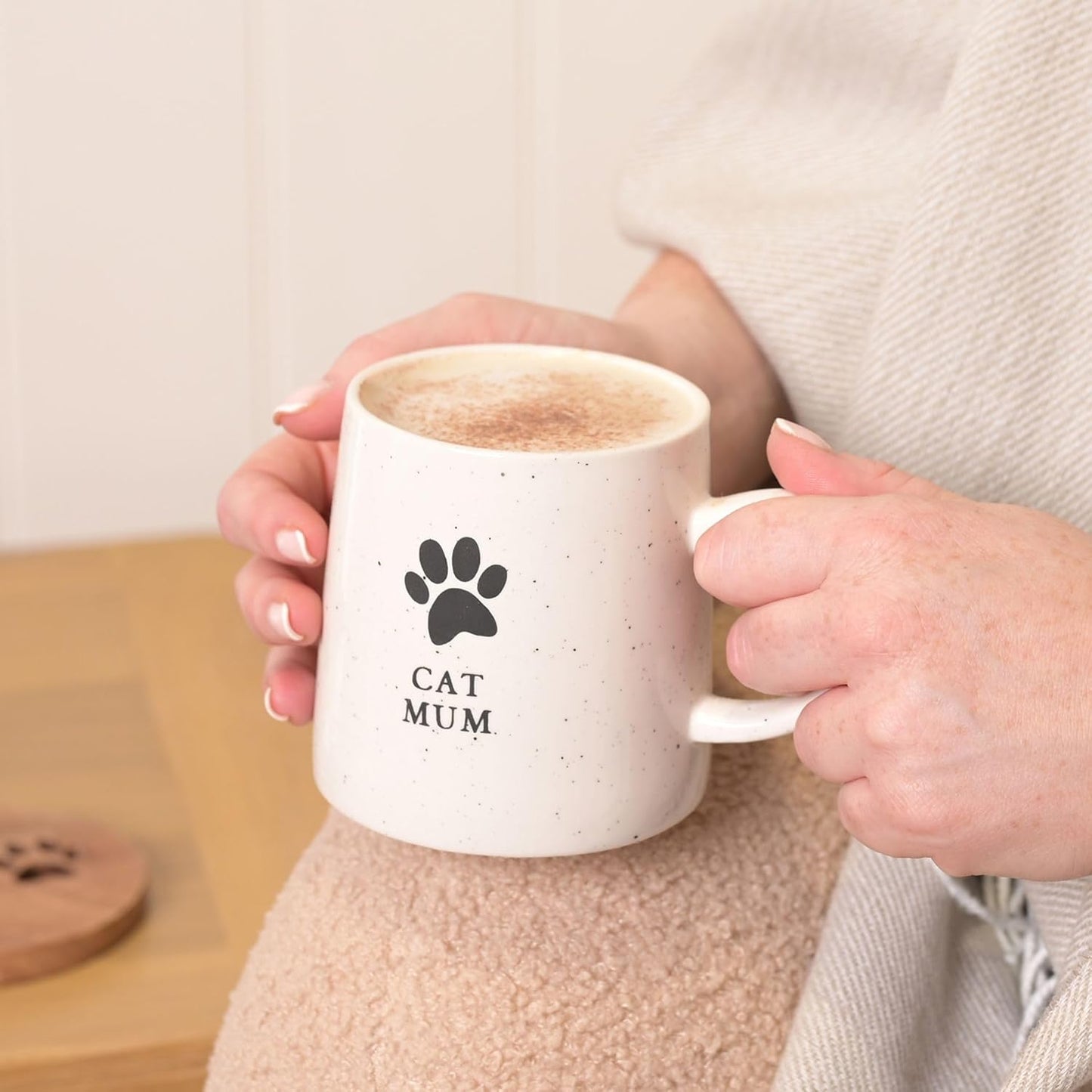 Person holding a white mug with 'Cat Mum' text and paw print design.