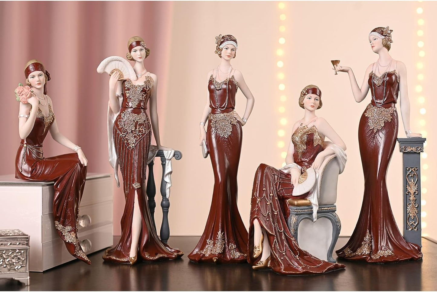 Set of decorative figurines of women in elegant dresses against a pink curtain background