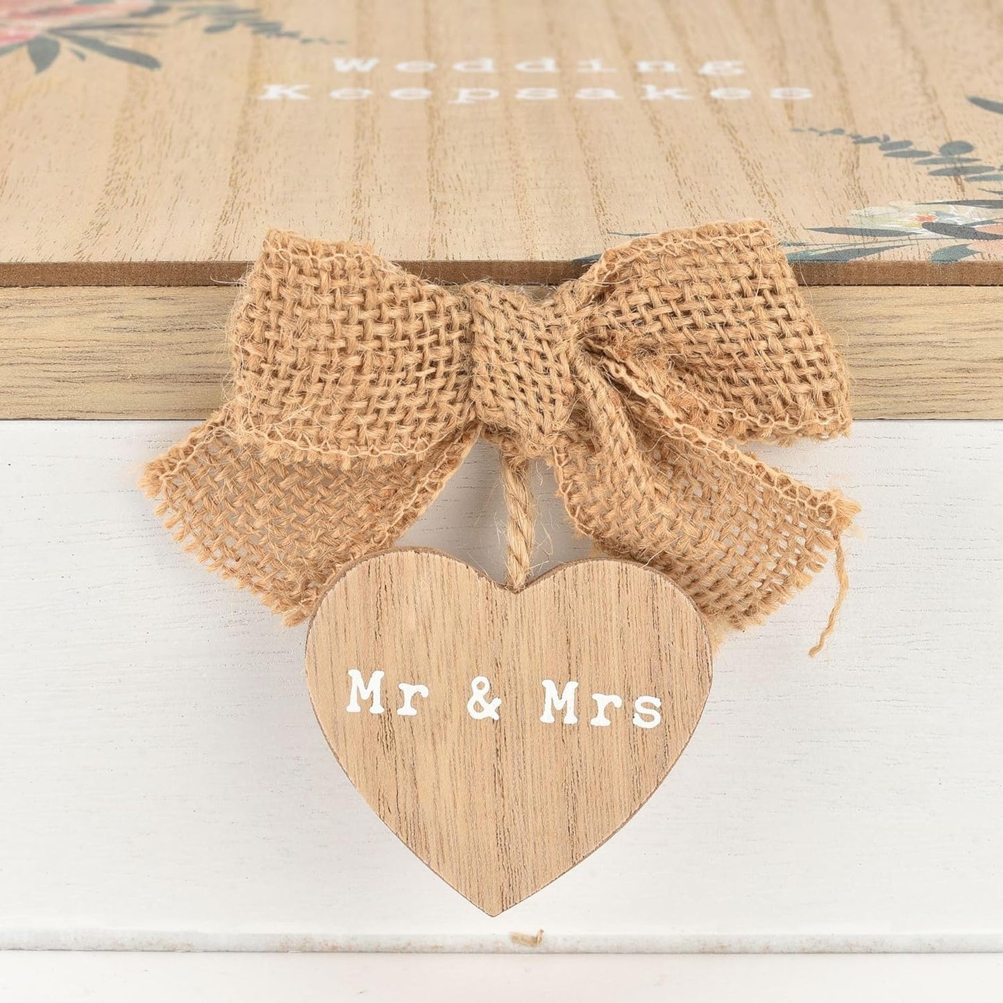 Wooden heart-shaped sign with 'Mr & Mrs' text and burlap bow on a floral background
