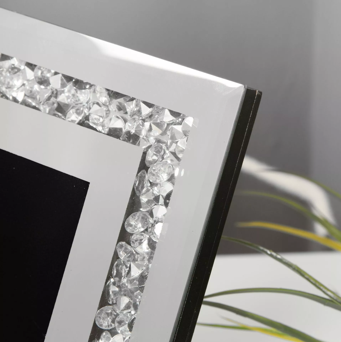 Decorative photo frame with crystal embellishments on a neutral background