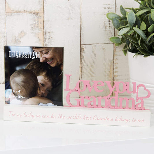 A pink 4x4 inch photo frame with 'Love You Grandma' inscription and a graphic of a grandmother hugging her grandchildren. In front is a photo of a grandmother with her grandchildren.