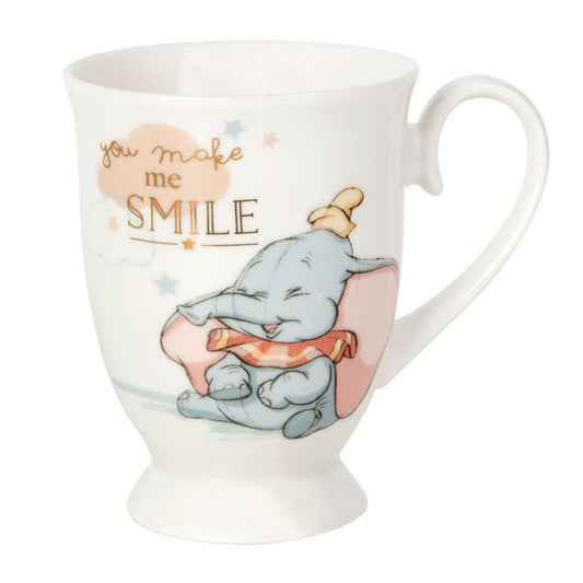 A white porcelain mug with an illustration of a baby-sized elephant character, presumably Dumbo, with the text 'You make me smile' in gold foil lettering.