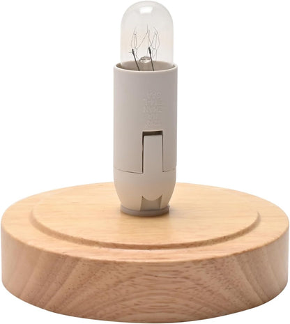 A miniature light bulb with a clear glass capsule and a beige plastic base, displayed on a round, light-colored wooden base against a white background.