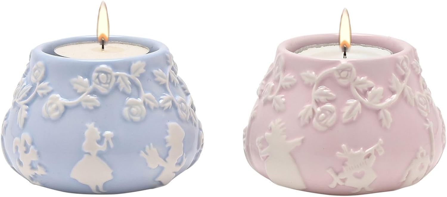 Two lit candles in decorative ceramic holders with floral patterns.