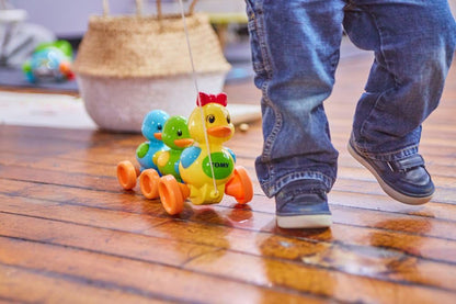 Child playing with a colorful toy duck on a wooden floor