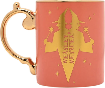 A Orange ceramic mug with a metallic gold handle and a gold wizard silhouette graphic featuring the text 'WEASLEY & WEASLEY' on the front.
