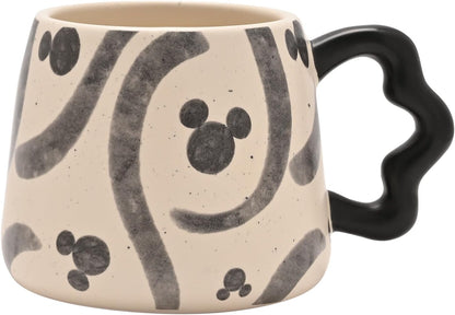 Ceramic mug with black abstract patterns and a black handle on a beige background