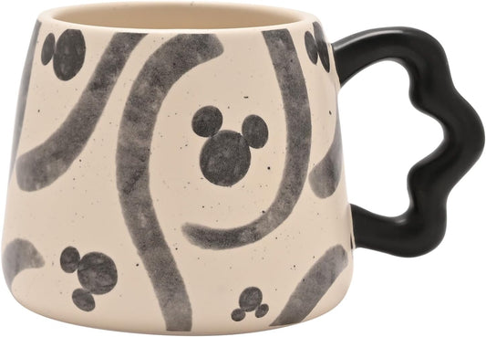 Ceramic mug with black abstract patterns and a black handle on a beige background