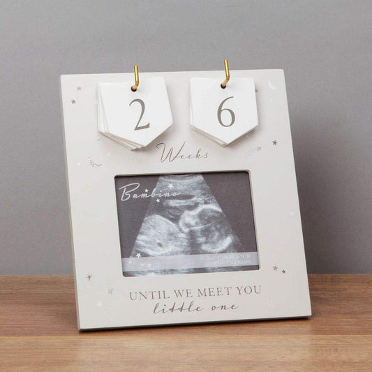 Baby countdown frame with ultrasound photo and 'Until we meet you, little one' text on a wooden surface.
