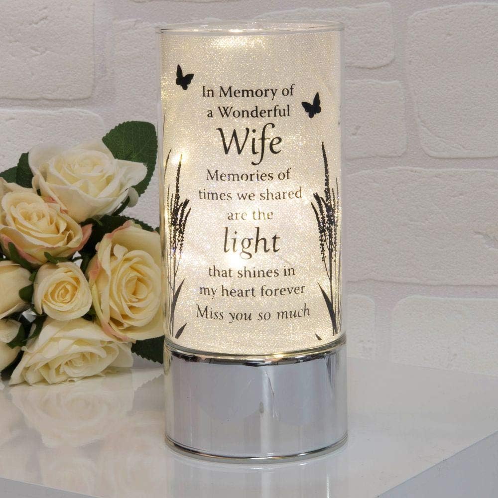 Memorial candle with engraved text and a bouquet of roses on a white background