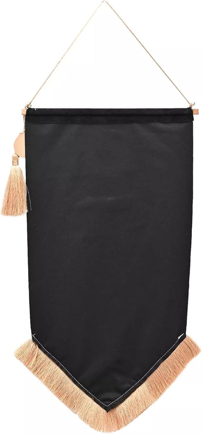 A black fabric wall banner with a pointed bottom, beige fringe trim, and a hanging cord with a tassel, shown against a plain white background.
