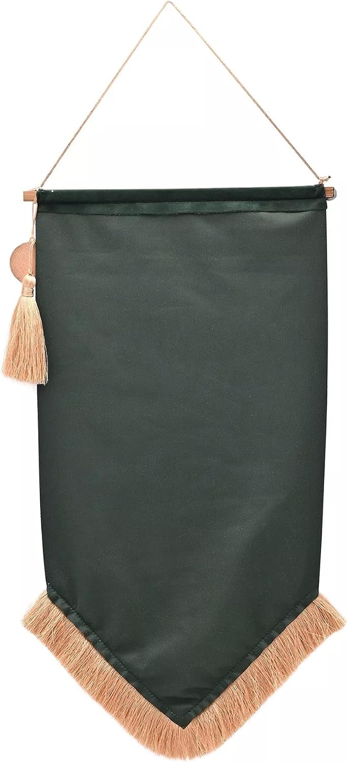 A dark forest green fabric wall banner with a pointed bottom, finished with a light tan fringe and a matching tassel, hanging from a thin cord.