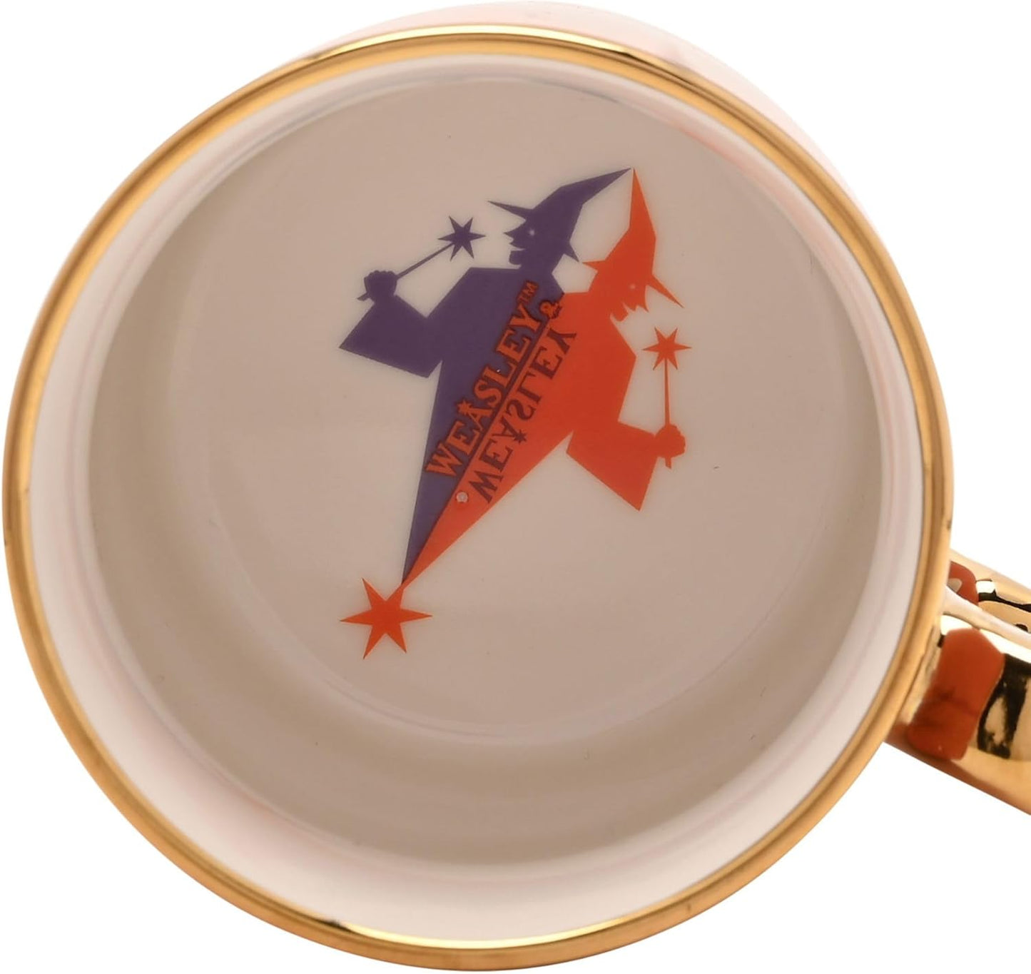 Close-up of a white ceramic mug interior with a gold rim, featuring a retro-style graphic of two witches in purple and orange with the text 'WEALSLEY'