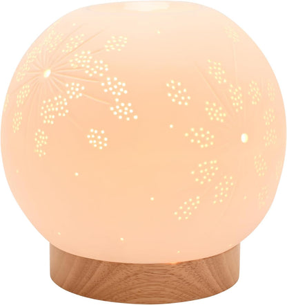 A spherical LED night light with a warm peachy-orange glow, featuring laser-cut floral and star patterns on its semi-translucent dome and resting on a round wooden base.
