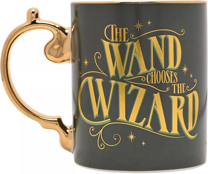 A dark green ceramic mug with a gold handle and rim, featuring the phrase 'THE WAND CHOOSES THE WIZARD' in stylized gold lettering with green shadowing and gold stars.