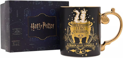 A black ceramic Harry Potter mug with a gold cauldron design and handle, shown next to its dark blue branded gift box.