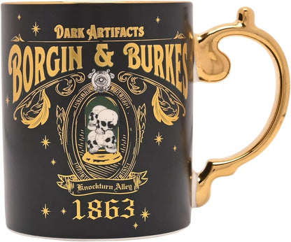 A black ceramic mug with a gold handle and gold printed gothic-style text reading 'Borgin & Burkard' and 'Dark Artifacts,' plus a skull under a glass dome illustration and the year 1863, on a white background.