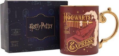 A Harry Potter Hogwarts Express ceramic mug in dark red with gold lettering and a gold handle, shown next to its dark blue branded gift box.