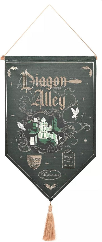 A hanging decorative wall banner featuring the text 'Diagon Alley' in ornate lettering, with illustrated owl, bird, house, and wand motifs on a dark green background. The banner has a wooden hanger at the top and a tassel at the bottom.