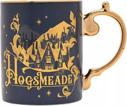 A dark navy blue ceramic mug with a metallic gold Hogsmeade castle illustration and ornate gold lettering, featuring a sculpted gold handle on a white background.