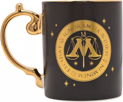 A glossy black ceramic mug with a gold metallic handle and a gold circular seal featuring the scales of justice and the Latin phrase