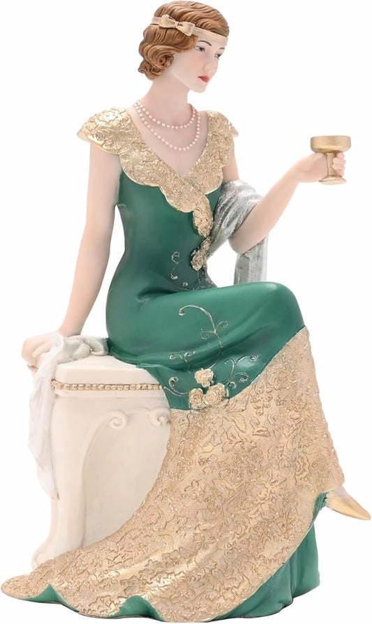 Decorative figurine of a woman in an elegant green and gold dress holding a candle.