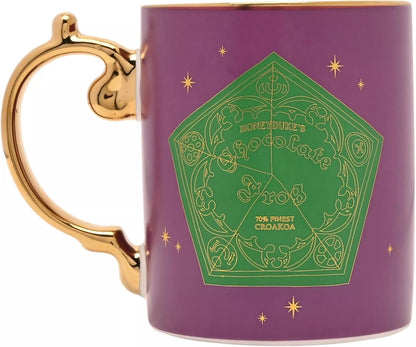 A purple ceramic mug with a gold-trimmed handle and rim, featuring a green pentagonal Hogwarts Chocolate Trio design with gold lettering and star accents on a white background.