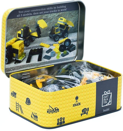 Toy construction set in a tin with yellow and black design, featuring toy trucks and building blocks.