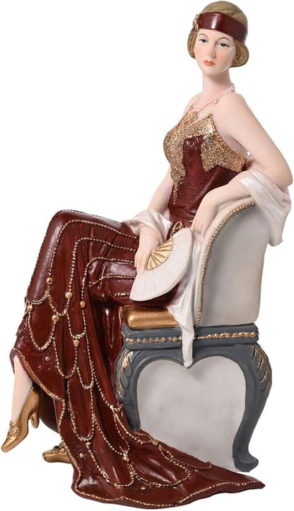 Decorative figurine of a woman in an elegant dress sitting on a chair.