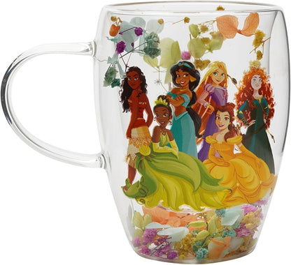 A clear glass mug featuring a colorful illustration of Disney Princesses inside, with dried flowers and leaves embedded in the glass.