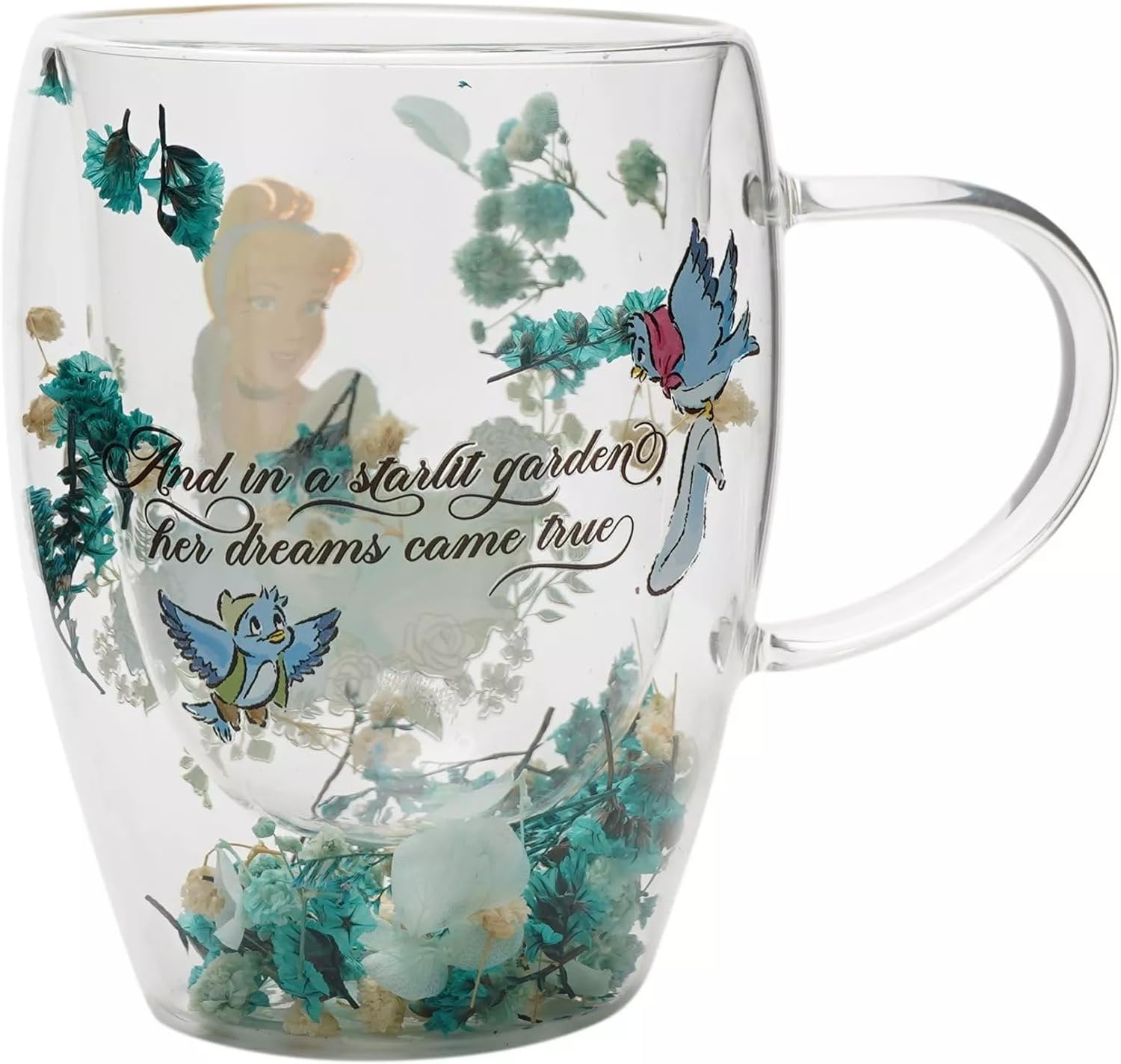 A clear glass mug featuring a printed design of a fairy, bluebirds, dried flowers, and the cursive quote 'And in a starlit garden her dreams came true'.