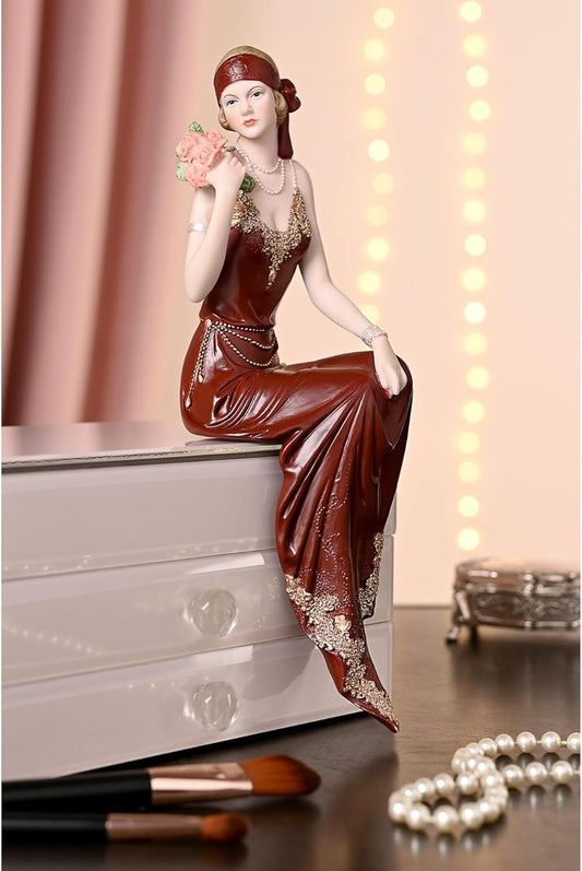 Decorative figurine of a woman in a long red dress with jewelry on a surface.