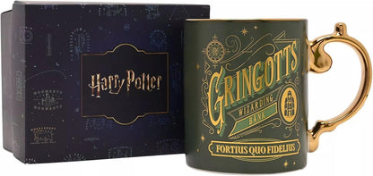 A dark green Harry Potter Gringotts Wizarding Bank mug with a gold handle and gold lettering, shown next to its dark blue presentation box featuring the Harry Potter logo.