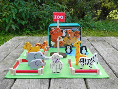 Wooden animal toys on a green mat with a 'Zoo' sign, outdoors.