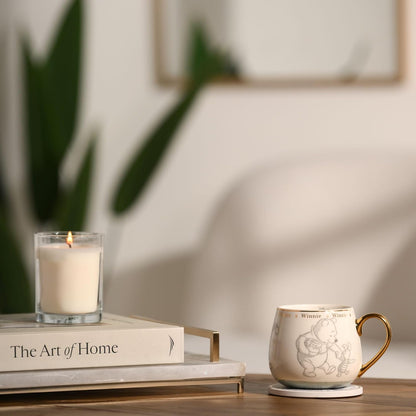 Candle, book, and mug on a table with a blurred background