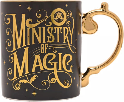 A black ceramic mug with a metallic gold handle and 'Ministry of Magic' text printed in gold on the side, shown against a plain white background.