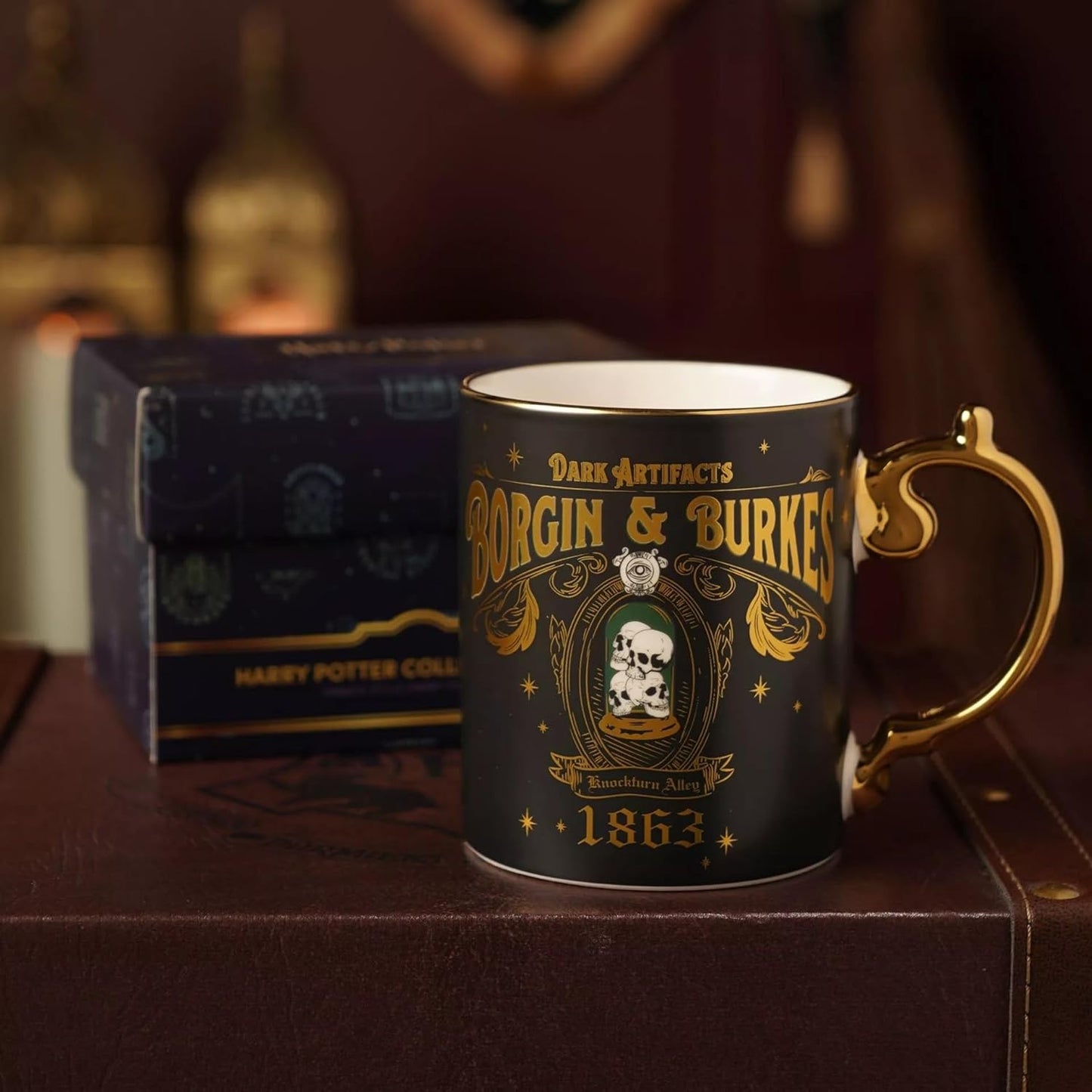 Mug with 'Borgin & Burkes' design on a wooden surface with a box in the background
