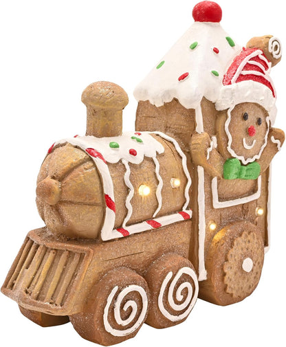A gingerbread-themed Christmas train figurine decorated with white icing, red and green candy accents, a Santa hat, and small warm white lights, shown on a plain white background.