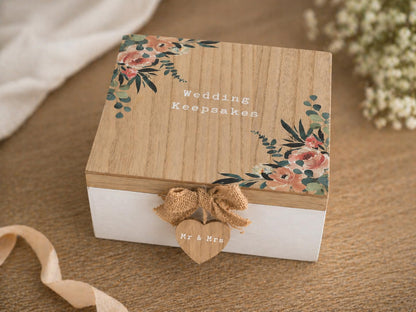 Wooden wedding keepsakes box with floral designs and a heart-shaped 'Mr. & Mrs.' tag on a wooden surface.