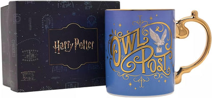 A blue ceramic Harry Potter Owl Post mug with gold lettering and a gold handle, shown next to its dark navy blue packaging box.