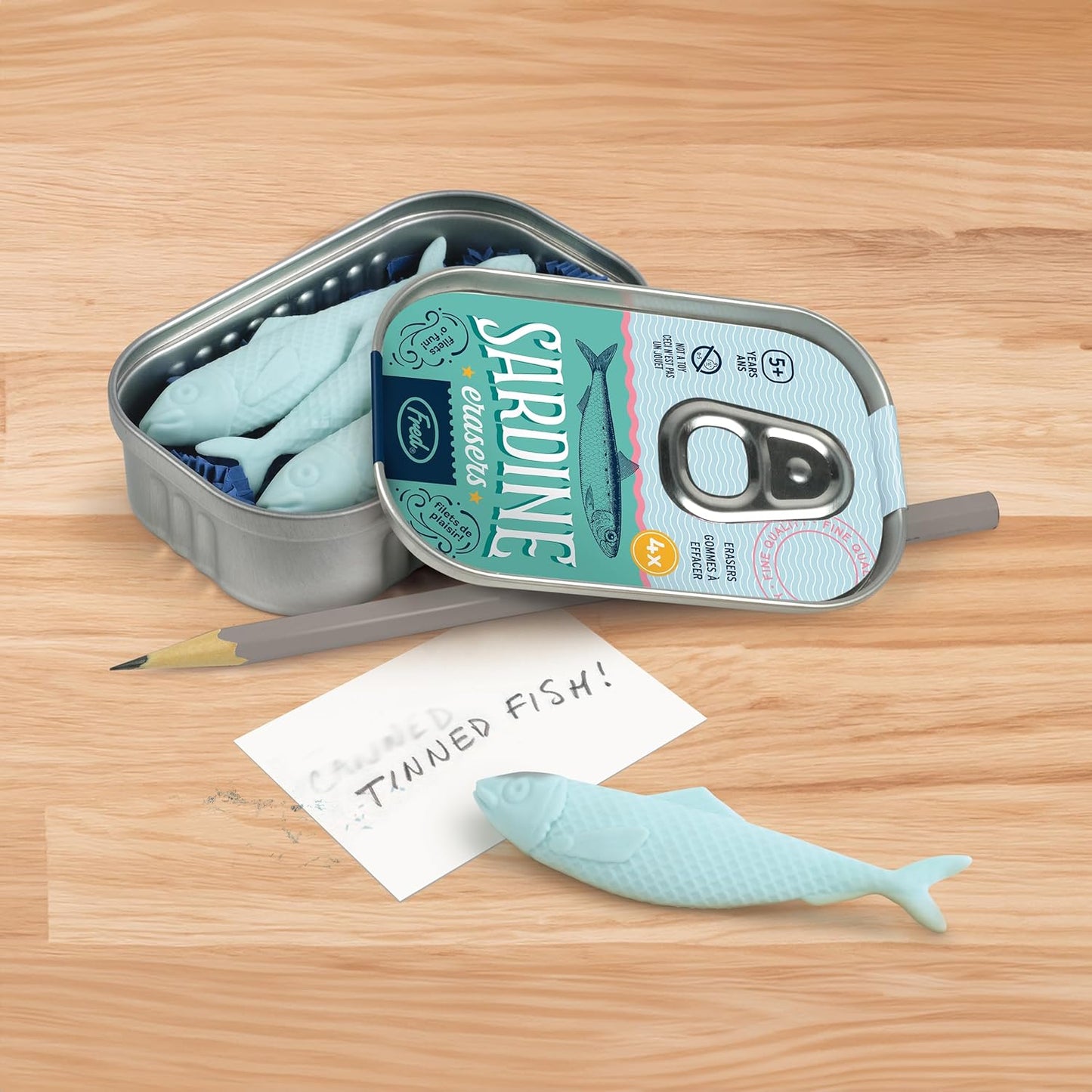 Sardine can-shaped pen with a fish design on a wooden surface
