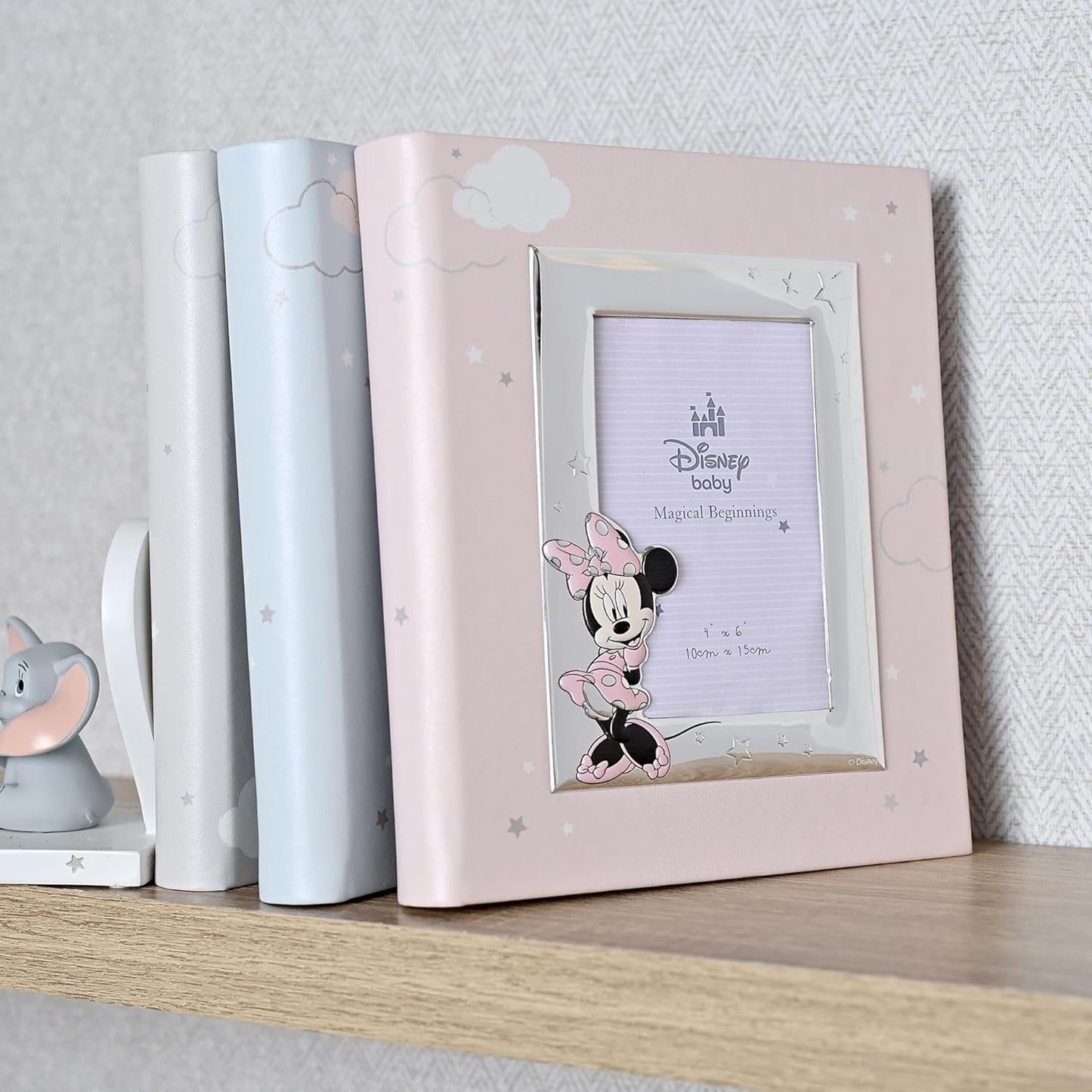 Pink photo frame with Minnie Mouse design on a shelf against a light gray wall.