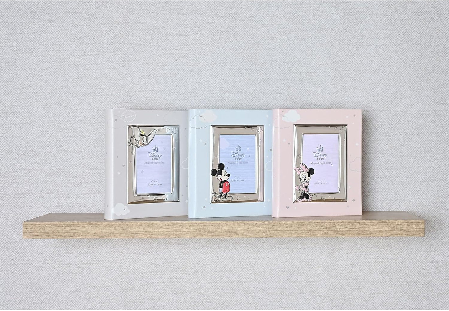 Three pastel-colored picture frames on a wooden shelf against a light gray wall.
