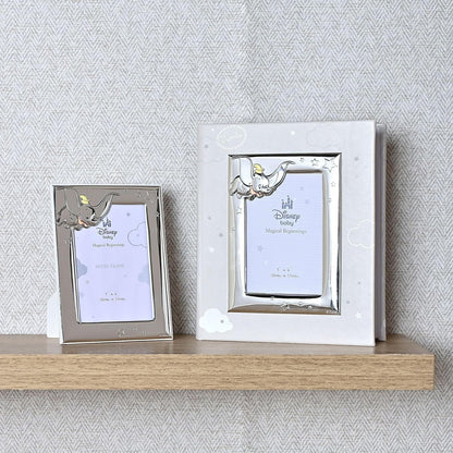 Two decorative photo frames with elephant designs on a wooden shelf against a textured wall.