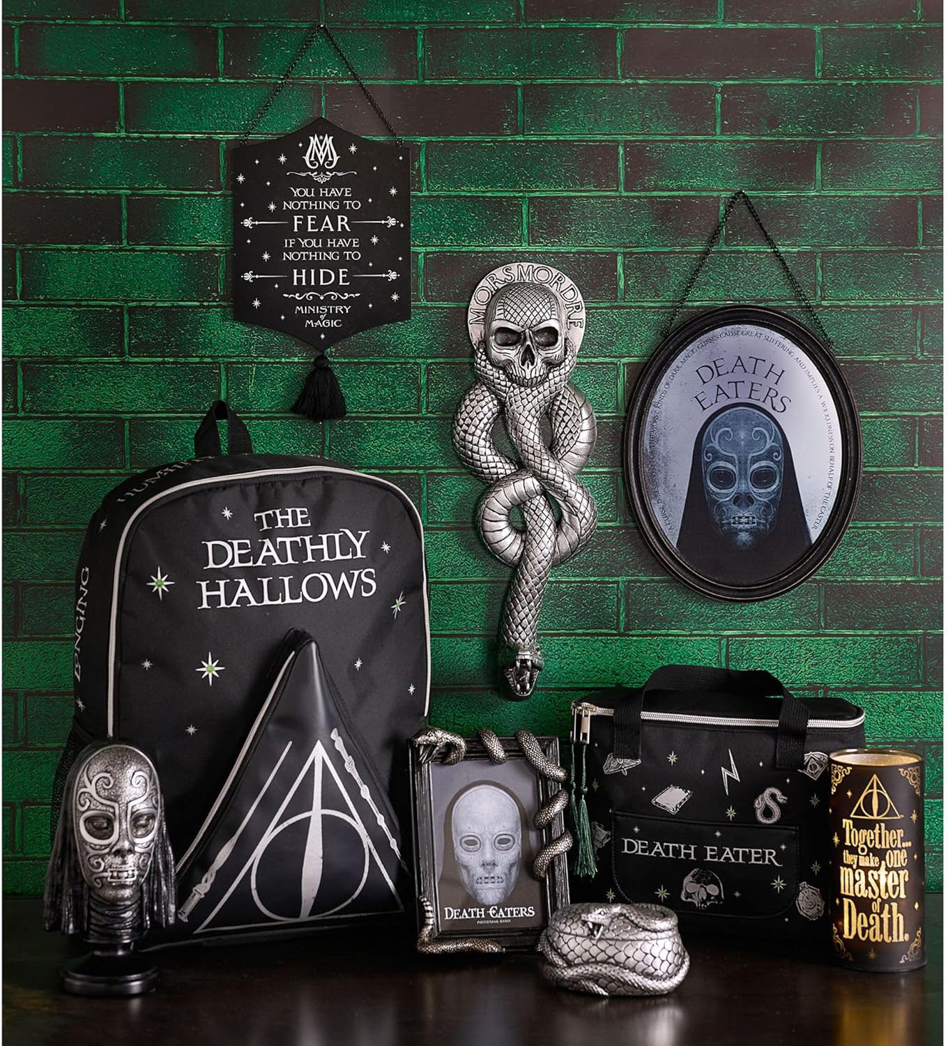 Collection of Deathly Hallows-themed merchandise against a green brick wall.