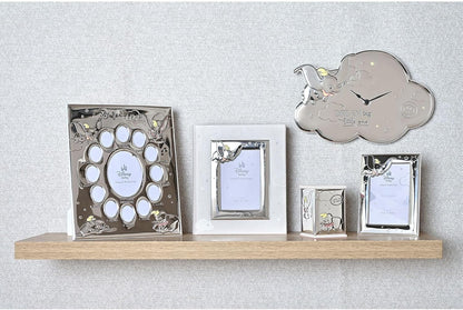 Collection of silver photo frames on a wooden shelf against a light gray wall.