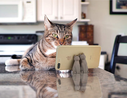 Cat using a phone with a cat-shaped stand on a kitchen counter